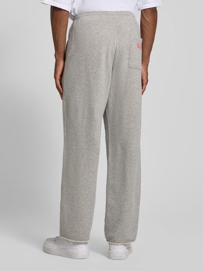 Männermodel trägt Sweatpants mit Eingrifftaschen Modell 'NYZZOW' von American Vintage aus Baumwoll-Elasthan-Mix, Wide Leg, Elastischer Bund und Tunnelzug, Innenbeinlänge bei Größe M 78 cm, Ganzkörperansicht Rückansicht.