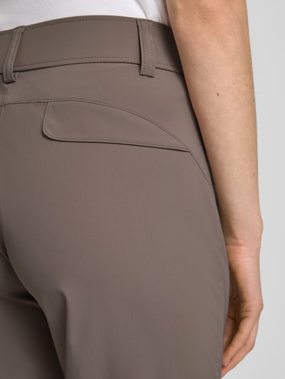 Kobiece model prezentuje spodnie materiałowe w kolorze taupe, model 'NATINA' od Raffaello Rossi, elastyczna mieszanka materiałów, dopasowany krój, kieszenie zapinane na zamek błyskawiczny, długość 7/8, szerokość w rozmiarze 36: 40 cm, długość wewnętrzna nogawki: 69 cm, zbliżenie na górną część tylnej nogawki
