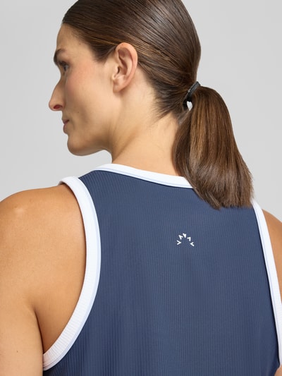 Frauenmodel trägt Top mit Rundhalsausschnitt Modell 'Tegan' von VARLEY in Dunkelblau mit weißen Rändern, elastischer Material-Mix, taillierte Passform, Rückenlänge bei Größe S 62 cm, Nahaufnahme Rückansicht.
