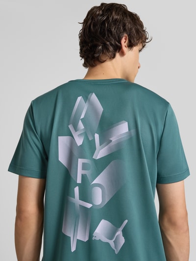 Männermodel trägt Regular Fit Sport-T-Shirt mit Logo-Print Modell 'M PUMA X HYROX' von PUMA in Grün, Ganzkörperansicht Rückansicht. Herren Sport-T-Shirt von PUMA Performance.