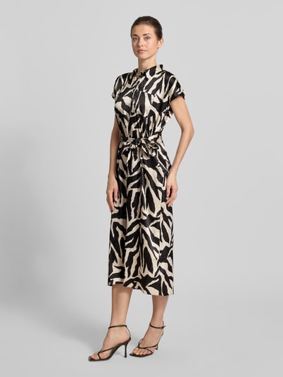 Vrouwenmodel draagt overhemdjurk met borstzak en strikceintuur van Apricot, zwart-beige zebra dessin, materiaalmix met stretch, getailleerd model, midi-jurk met overhemdkraag, knoopsluiting, ruglengte maat S 123 cm, borstwijdte 48 cm, mouwlengte 3 cm, geheel lichaamsaanzicht vooraan.