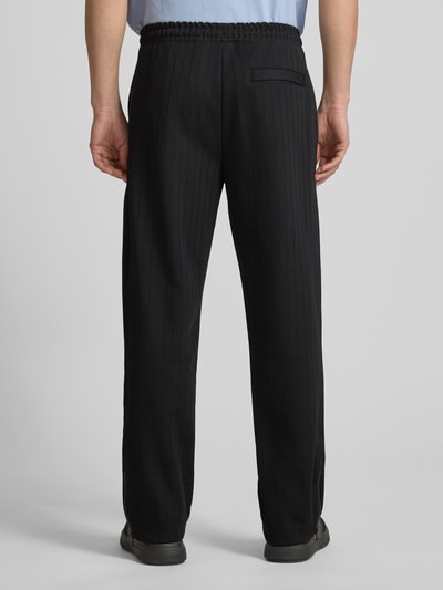 Männermodel trägt Regular Fit Sweatpants aus Baumwoll-Mix Modell 'DAVROPANT' von HUGO, Optik: Unifarben, Muster: gestreift, Label Patch, Label Stitching, Tunnelzug, Bundabschluss: elastisch, seitliche Eingrifftaschen, Materialverarbeitung: Sweat, Beinabschluss mit Seitenschlitz und Reißverschluss, Ganzkörperansicht Rückansicht.