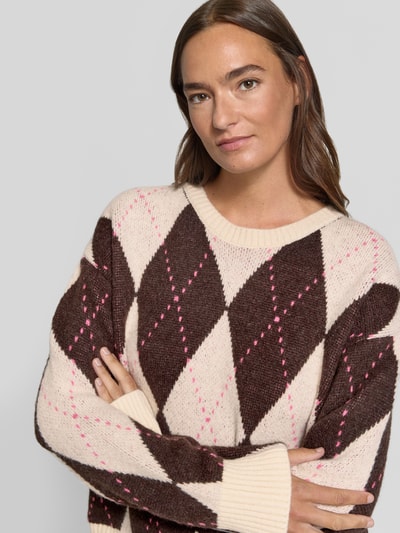 Vrouwenmodel draagt Strickpullover im Allover-Look met Rundhalsausschnitt van Milano Italy, Materiaalmix met alpaca, relaxed fit, all-over look, ronde hals, ruglengte bij maat S 54 cm, mouwlengte bij maat S 55 cm, crèmekleurig met bruin en roze ruiten, zachte gebreide textuur, Nahaufnahme bovenlichaam.