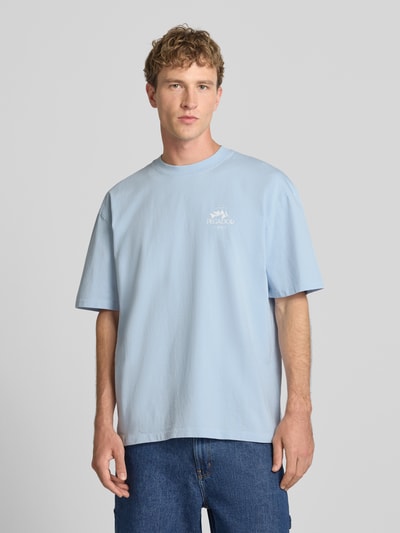 Männermodel trägt Oversized T-Shirt mit Backprint und Rundhalsausschnitt von PEGADOR in Hellblau, reine Baumwolle, Nahaufnahme Oberkörper.