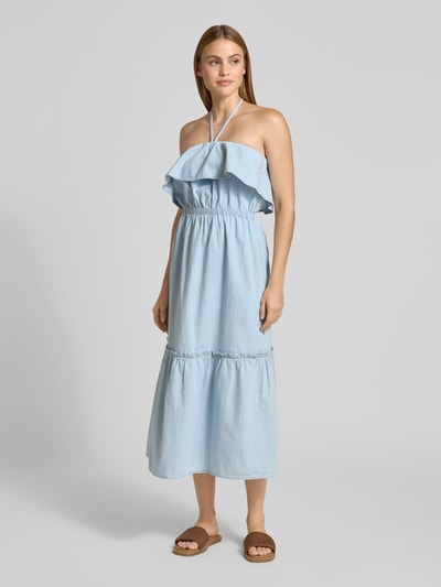 Frauenmodel trägt Jeanskleid mit Neckholder Modell 'LUMIRA' von Drykorn aus Reiner Baumwolle, Taillierter Schnitt, Midikleid, hellblau, Volant am Ausschnitt, Ganzkörperansicht von vorne.