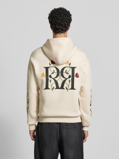 Männermodel trägt Regular Fit Hoodie mit Logo-Stitching von REVIEW, florale Stickereien, cremefarbend, Känguru-Tasche, Ganzkörperansicht Rückansicht