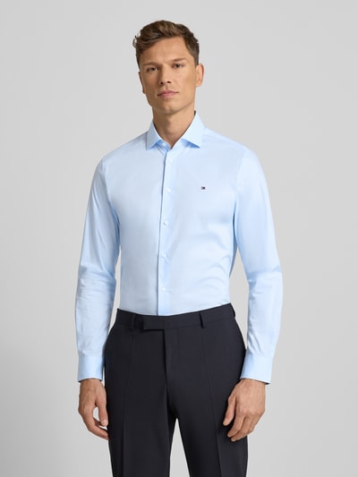 Męski model nosi Slim Fit Businesshemd aus Baumwoll-Mix von Tommy Hilfiger, efekt: jednolity kolor, kołnierzyk typu kent, wyhaftowane logo, listwa guzikowa na całej długości, długi rękaw z mankietami sportowymi, popelina, mieszanka bawełny; całkowity widok z przodu.