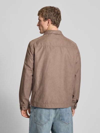Męski model nosi Jacke mit Umlegekragen Modell 'DYLAN' od Jack & Jones, krój regular fit, kolor beżowy, materiał gładki, zdjęcie całej sylwetki z tyłu. Długość pleców w rozmiarze M: 70 cm, szerokość ramion w rozmiarze M: 44 cm, szerokość klatki piersiowej w rozmiarze M: 52 cm, długość rękawa w rozmiarze M: 65 cm.