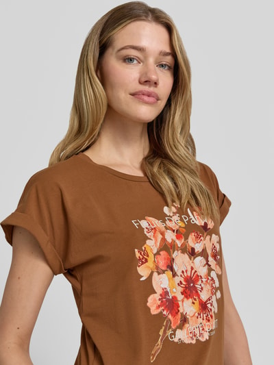 Frauenmodel trägt Damen T-Shirt mit Motiv-Print Modell 'RINA' von Soyaconcept, Braun mit Blumenprint, Baumwoll-Elasthan-Mix, Regular-Fit, Rundhalsausschnitt, Ärmel mit Aufschlag, Rückenlänge bei Größe S 61 cm, Nahaufnahme Oberkörper.