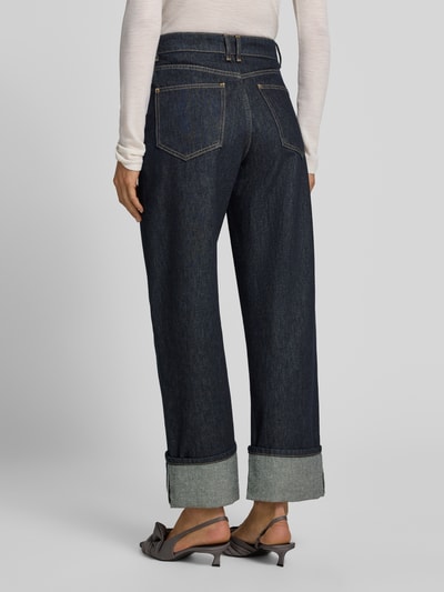 Vrouwenmodel draagt Raw Denim Jeans mit weitem Umschlag van Style Icon Collection, puur katoen, wide fit, 5-pocketmodel, riemlussen, knoop- en ritssluiting, bandwijdte maat 36: 35 cm, binnenbeenlengte maat 36: 82 cm, denim, donkerblauwe kleur, grove structuur, rechte vormen, wijde pijpen, detail van de omslag, cropped lengte, textuur zichtbaar, Ganzkörperansicht Rückansicht.
