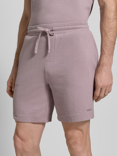 Męski model nosi Regular Fit Sweatshorts aus Baumwoll-Mix Modell 'AUSTIN' od HUGO, kolor jednolity, wafel, krój regular fit, bawełna, elastyczny pas, boczne kieszenie, widok na całe ciało z przodu.