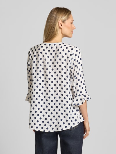Frauenmodel trägt Blusenshirt mit Viskose-Anteil von Apricot, weiß mit dunkelblauen Punkten, 3/4-Arm, gerader Schnitt, Ganzkörperansicht Rückansicht.
