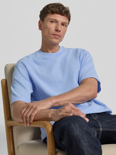 Männermodel trägt Relaxed Fit T-Shirt aus reiner Bio-Baumwolle Modell 'MAARKOS WAFFLE' von Armedangels in Optik: Unifarben mit Waffel-Struktur, Logo-Stitching, Rundhals, Kurzarm, Feinstrick, Nahaufnahme Oberkörper.