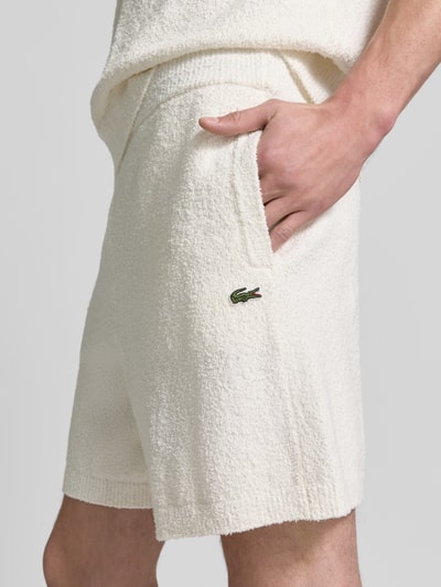 Männermodel trägt Relaxed Fit Sweatshorts aus Baumwoll-Mix von Lacoste, Optik: Unifarben, Applikation: Label Patch, Materialverarbeitung: Bouclé, Nahaufnahme Oberschenkel.