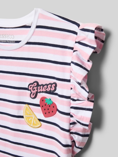 Meisje draagt T-shirt met ruches en logo van guess, mix van katoen en elastaan, regular fit, logoprint, ronde hals, detailopname.