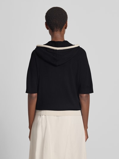 Frauenmodel trägt Relaxed Fit Hoodie aus Woll-Mix von Marc Cain in Schwarz mit Strick-Optik, Halbarm, elastische Abschlüsse, Rückenansicht.