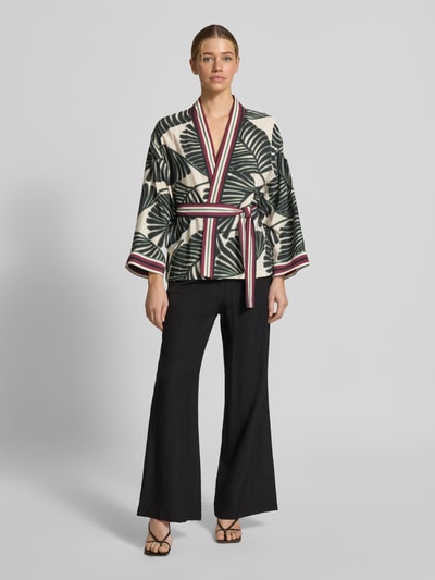 Frauenmodel trägt Kaftan aus Viskose-Mix mit floralem Allover-Print von Christian Berg Woman Selection, taillierte Passform, Stoffband, Farben Creme, Dunkelgrün und Rot, Rückenlänge 66 cm, Brustweite 60 cm, Ärmellänge 48 cm, Ganzkörperansicht von vorne.