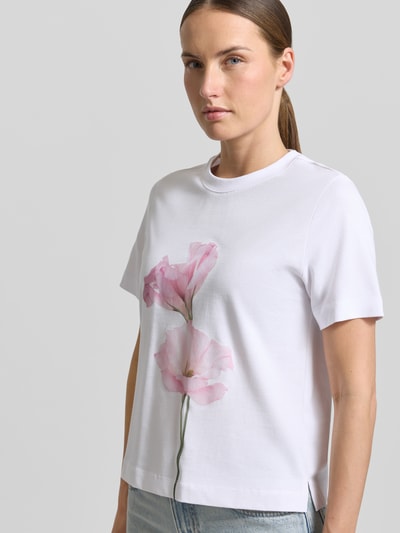 Frauenmodel trägt T-Shirt mit Motiv-Print Modell 'FIORE' von Stefanel, weiße Baumwolle, gerader Schnitt, Nahaufnahme Oberkörper.