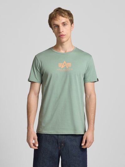 Männermodel trägt T-Shirt mit Logo und Rundhalsausschnitt von Alpha Industries in Grün, Reine Baumwolle, Regular-Fit, Logo, Rückenlänge 67 cm, Ganzkörperansicht von vorne.