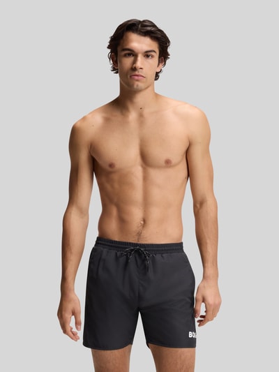 Männermodel trägt Badehose mit Paspelnaht in Kontrastfarbe Modell STARFISH von BOSS, unifarben, Label-Schriftzug, Popeline, Ganzkörperansicht von vorne.