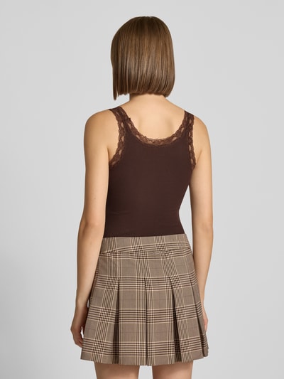 Młody modelka nosi brązowe body Slim Fit Body aus Baumwoll-Mix Modell 'VINI' von ONLY, tkanina prążkowana, spódnica w kratę, całkowity widok z tyłu, damskie body od ONLY.