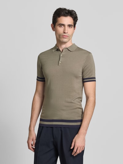 Męski model nosi Slim Fit Poloshirt aus Lyocell-Seide-Mix od GUESS, model 'LARRY', kołnierzyk polo, listwa guzikowa, paski w kontrastowym kolorze, długość tyłu w rozmiarze M: 67 cm, koszulka polo w kolorze oliwkowym z gładką teksturą, widok całej sylwetki od przodu.