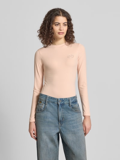 Frauenmodel trägt Slim Fit Longsleeve mit Logo-Detail von ANOTHER COTTON LAB in Beige, elastischer Baumwoll-Mix, Ganzkörperansicht von vorne.