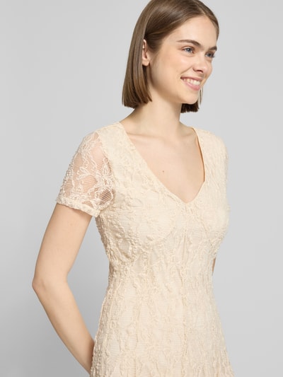 Frauenmodel trägt Slim Fit Minikleid aus Spitze Modell 'ALBINA' von Only, cremefarben, V-Ausschnitt, Spitzenmuster, Nahaufnahme Oberkörper.