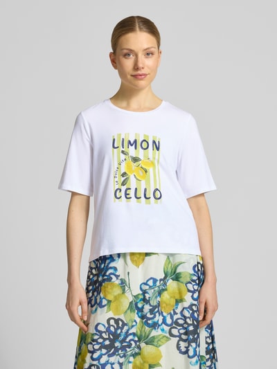 Vrouwenmodel draagt T-Shirt met Motiv-Print van More & More, wit met geel motief, regular fit, katoen-elastaan mix, ronde hals, vooraanzicht volledige opname.