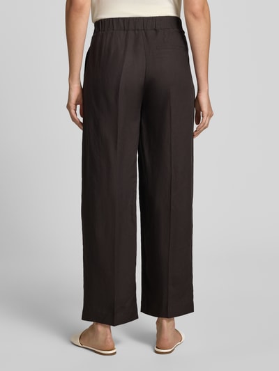 Vrouwenmodel draagt Wide Fit broek uit viscosemix met linnenmodel 'Cisilia' van Someday, zwart met band- en persplooien, volledige achteraanzicht. Context: dames broek van Someday, viscosemix met linnen, wide fit, model 'Cisilia', bandplooien, persplooien, haakjes- en ritssluiting, bandwijdte maat 36: 43 cm, binnenbeenlengte maat 36: 74 cm.