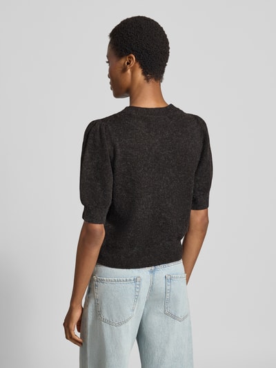 Frauenmodel trägt Regular Fit Pullover mit Puffärmeln von VERO MODA in Dunkelgrau zu heller Jeans, Textur grobstrick, Ganzkörperansicht Rückansicht.