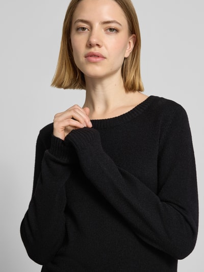 Frauenmodel trägt Strickpullover aus Viskose-Mix mit Rundhalsausschnitt von Vila, Regular-Fit, schwarze Struktur, Nahaufnahme Oberkörper. Rückenlänge 60 cm, Ärmellänge 60 cm, Modell 'Viril', Größe S.