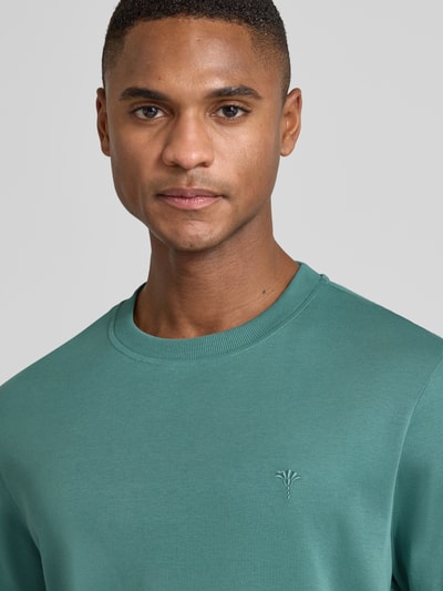 Männermodel trägt T-Shirt mit Label-Stitching Modell 'Priamo' von JOOP! Collection in Grün, reine Baumwolle, Nahaufnahme Oberkörper