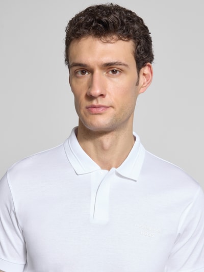 Männermodel trägt weißes Regular Fit Poloshirt aus reiner Baumwolle, Label-Schriftzug, Polokragen, BOSS Green X PORSCHE, Nahaufnahme Oberkörper.