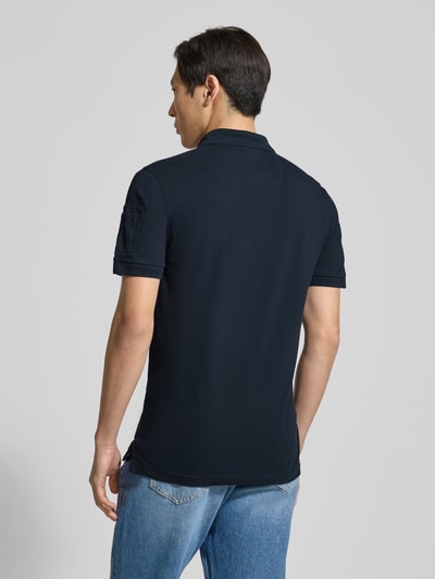 Männermodel trägt dunkles Slim Fit Poloshirt aus Baumwoll-Elasthan-Mix mit Label-Stitching von PME Legend, Rückenlänge 74 cm, Ganzkörperansicht Rückansicht.