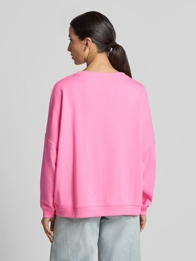 Vrouwenmodel draagt oversized sweatshirt van puur katoen Model 'Sweet Soul' van miss goodlife in effen roze, elastische boorden, met strass-steentjes en statementprint, helemaal effen oppervlak, ronde hals, Ganzkörperansicht Rückansicht.