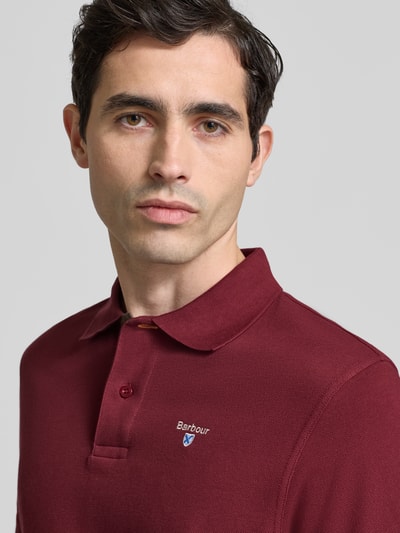 Männermodel trägt Regular Fit Poloshirt aus reiner Baumwolle von Barbour in effen kleuren, piqué, labelstitching, 2-knoopsluiting, korte mouw, Nahaufnahme Oberkörper.