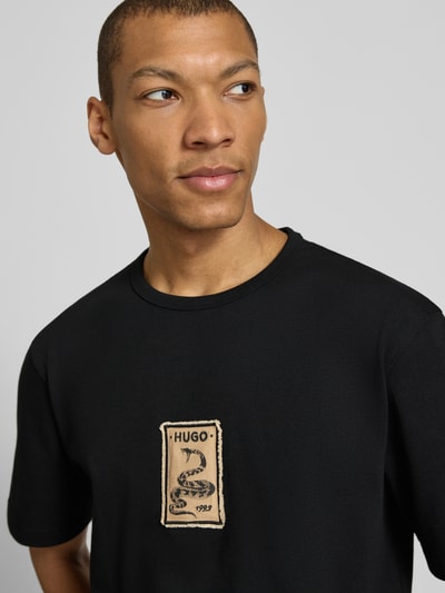 Männermodel trägt Regular Fit T-Shirt aus reiner Baumwolle Modell 'DOBUL' von HUGO in Optik: Unifarben mit Label-Stitching-Applikation auf Feinripp, Nahaufnahme Oberkörper.