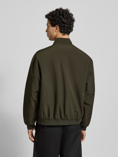 Männermodel trägt Regular Fit Jacke mit Stehkragen Modell 'Charge' von JACK & JONES in Oliv, elastische Abschlüsse, Eingrifftaschen, Rückenlänge 66 cm, Schulterbreite 49 cm, Brustweite 50 cm, Ärmellänge 64 cm, Ganzkörperansicht Rückansicht.