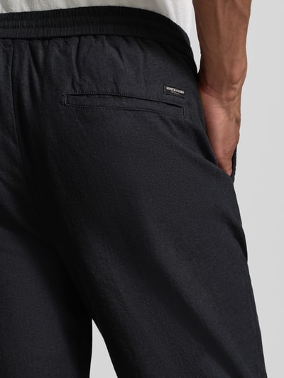 Männermodel trägt Jogpants aus Baumwoll-Leinen-Mix mit elastischem Bund von Scotch & Soda, Regular Fit, Detailaufnahme Rückansicht.