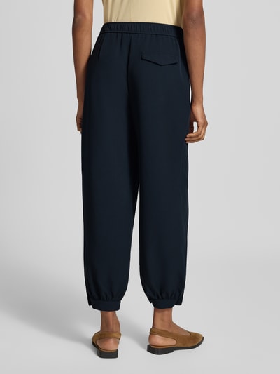 Frauenmodel trägt Weite Hose mit Viskose-Anteil Modell 'Myha balloon' von OPUS in dunklem Blau, lockerer Schnitt, glatte Textur, Damen Weite Hose von OPUS, Ganzkörperansicht Rückansicht.