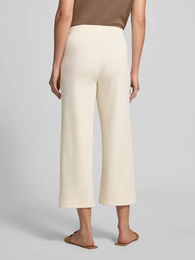 Männermodel trägt Wide Fit Sweatpants in verkürzter Passform Modell 'Banu' von Soyaconcept, elastyczna mieszanka materiałów z domieszką modalu, kremowy kolor, pas z tunelem, krój wide fit, skrócona długość, Ganzkörperansicht Rückansicht.