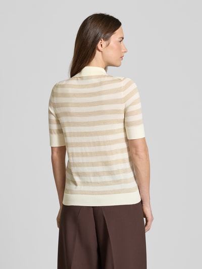 Frauenmodel trägt Regular Fit Poloshirt aus reiner Schurwolle Modell 'FIDENKA' von BOSS mit Allover-Streifenmuster in Beige, Feinstrick, Kurzarm, Rückansicht.