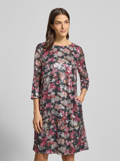 Kobiece model prezentuje Knielanges Kleid mit Allover-Muster und Paillettenbesatz von Christian Berg Woman, kwiatowy wzór na całej powierzchni, prosty krój, długość do kolan, okrągły dekolt, rękaw o dł. 3/4, cekinowe obszycie, czarno-różowe kolory, lekki połysk, czysta wiskoza, szerokość w rozmiarze 36: 48 cm, długość tyłu w rozmiarze 36: 96 cm, długość rękawa w rozmiarze 36: 47 cm. Ganzkörperansicht z przodu.