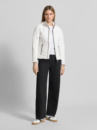 Frauenmodel trägt Slim Fit Jacke in Stepp-Optik von G.I.G.A. DX, weiß, Logo-Detail, Reißverschluss, Eingrifftaschen, Ganzkörperansicht von vorne