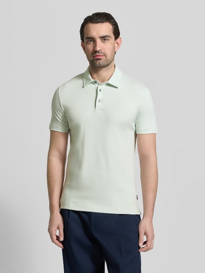 Männermodel trägt Slim Fit Poloshirt aus reiner Baumwolle Modell 'PALOSH 30' von BOSS in Unifarbe mit Polokragen, Ganzkörperansicht von vorne.