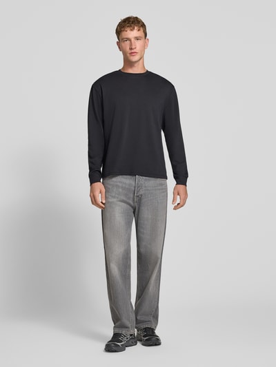 Männermodel trägt Relaxed Fit Langarmshirt aus Baumwoll-Mix Modell 'SCASPIAN' von ONLY, Herren T-Shirt, dunkle Farben, Ganzkörperansicht von vorne.