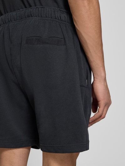 Männermodel trägt Shorts mit Logo-Stitching Modell 'ZANICA' von Ellesse aus Baumwoll-Mix, Relaxed-Fit, Gesäßtasche, Nahaufnahme Rückansicht.