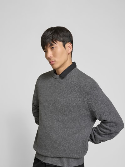 Männermodel trägt Pullover in Strick-Optik von ANNARR aus Reine Baumwolle in Grau, Relaxed-Fit, mit Rundhalsausschnitt, elastische Abschlüsse, Rückenlänge bei Größe M 72 cm, Ganzkörperansicht von vorne.