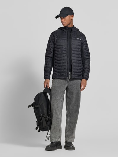 Mannelijk model draagt Gewatteerd jack met capuchon en logoprint van Columbia, regular fit, ritssluiting, ruglengte maat M 72 cm, schouderbreedte 47 cm, borstwijdte 52 cm, mouwlengte 69 cm, kleur zwart, Ganzkörperansicht van voren.